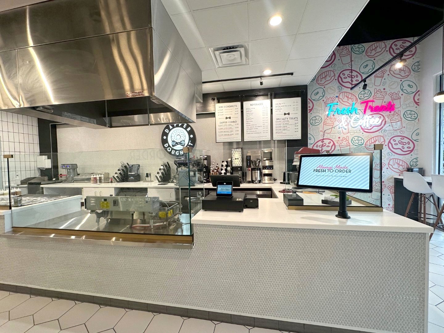 Dapper Doughnut counter with the open made-to-order station, menu boards, and neon Fresh Treats & Coffee sign