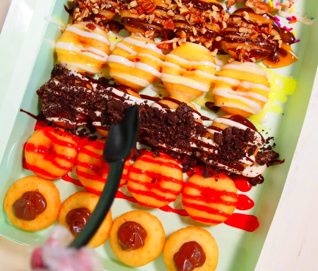 A tray of colorful, freshly decorated Dapper mini doughnuts